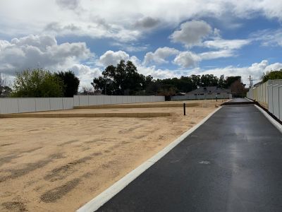 Retaining walls between white sand blocks with asphalt driveway running along right hand side